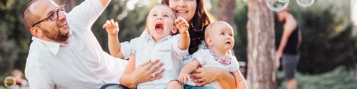 Joyful family enjoying a sunny day in the park while playing with bubbles.