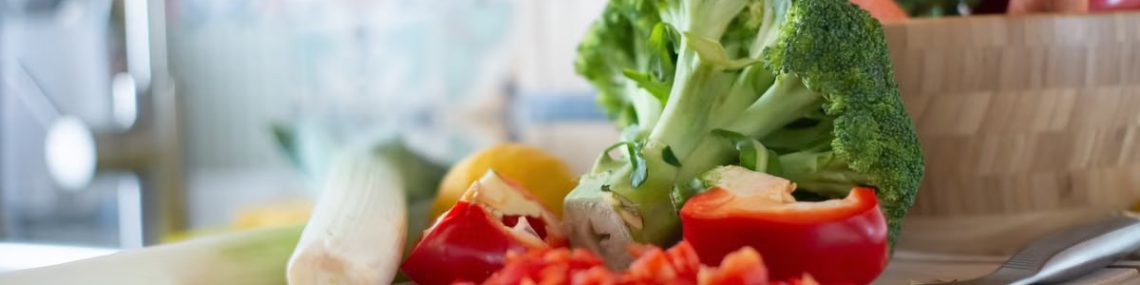 Colorful vegetables including broccoli and bell peppers on a chopping board, perfect for healthy cooking concepts.