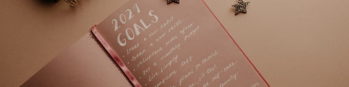 Top view of a 2021 goals notebook with handwritten list and star decorations, ideal for planning inspiration.